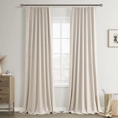 a white curtain hanging on the side of a window next to a dresser and chair