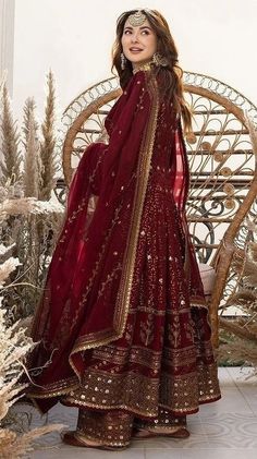 a woman in a red and gold outfit standing next to a chair with her hands on her hips