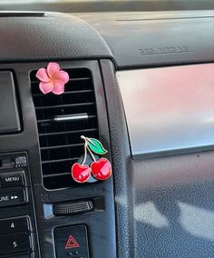 a car dashboard with two cherries attached to it's air ventilator