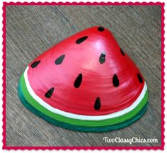 a watermelon shaped object sitting on top of a wooden floor next to a red frame