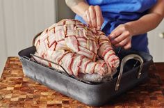 a person cutting up some meat in a pan