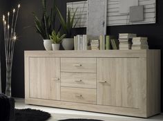 a living room with black walls and white carpeted flooring, a large wooden cabinet that has plants on it