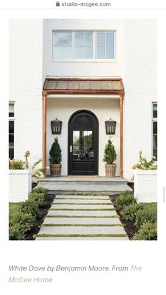 a white house with black front door and steps leading up to the front door area