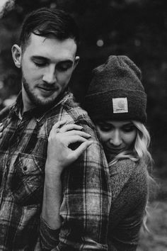 black and white photo of a man holding a woman's back while she is wearing a hat