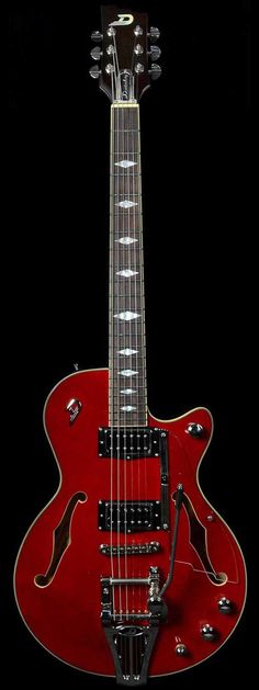 a red electric guitar sitting on top of a black surface with its neck up and head down