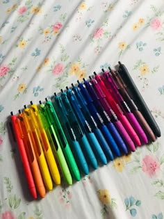 many different colored pens lined up on a bed