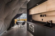 a kitchen with black cabinets and counter tops next to a dining room table in the background