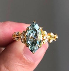 a person is holding a fancy ring with an aqua and yellow diamond in it's center