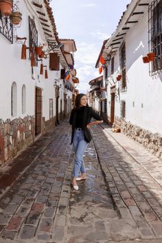 a woman is walking down the street in an old town with cobblestone streets