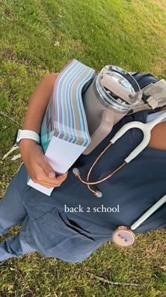 a man laying in the grass with his back to him holding a book and stethoscope