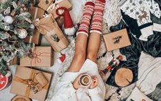 a woman laying on top of a bed next to christmas presents