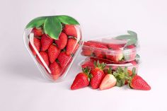 two plastic containers filled with strawberries next to each other