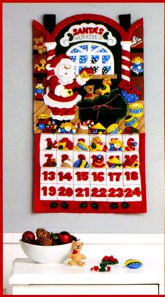 a christmas calendar hanging on the wall next to a bowl of fruit and teddy bears