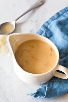 a bowl of soup on a blue cloth with two spoons