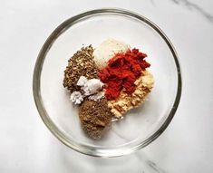 three different spices in a glass bowl on a marble counter top, with one red and the other white