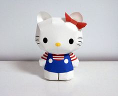 a hello kitty figurine sitting on top of a white table next to a wall