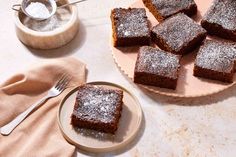 several pieces of brownies on a plate with powdered sugar next to it and a spoon