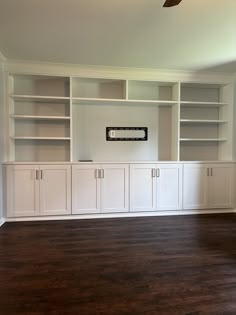 an empty room with white bookcases and wood flooring in the foreground