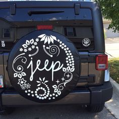 a jeep with the word jeep painted on it's back tire cover is parked in front of a house