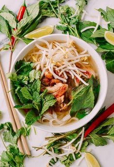 a white bowl filled with noodle soup and garnished with cilantro