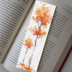 an open book with watercolor trees on it