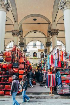 people are walking through an open market area