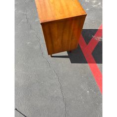 a wooden table sitting on top of a parking lot next to a red and white line