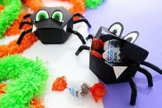 some candy bags are sitting on the table next to black paper spider puppets and orange streamers