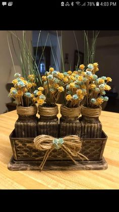 four vases with flowers in them sitting on a wooden table next to each other