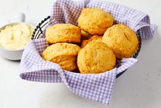 a basket filled with muffins next to a small bowl of cream cheese sauce