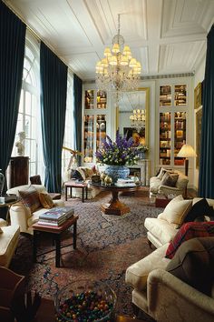 a living room filled with lots of furniture and a chandelier hanging from the ceiling