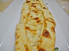 a white plate topped with lots of cheese covered flatbreads on top of each other