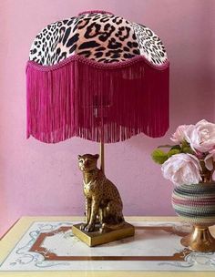 a lamp with a leopard print shade on it and a cat figurine next to it