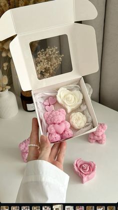 a person is holding an open box with fake flowers in it on a white table