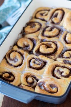 a pan filled with cinnamon rolls on top of a wooden table