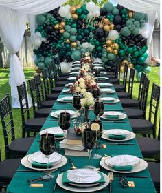 a long table is set with black and white plates, green napkins, and balloons