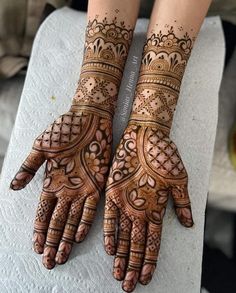 two hands with henna tattoos on them