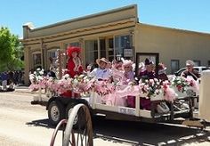 people are riding in the back of a truck with pink decorations on it's flatbed