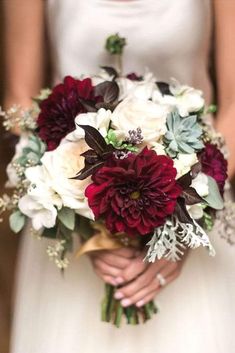 a bride holding a bouquet of red and white flowers