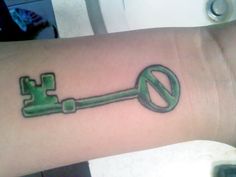 a green key tattoo on the wrist