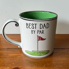 a white and green coffee mug with the words best dad by par on it sitting on a wooden table