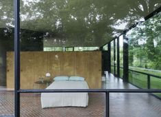 a bedroom with glass walls and brick flooring