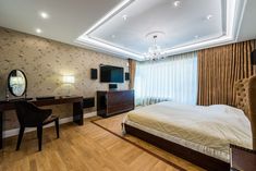 a bedroom with a bed, desk and television on the wall next to a window