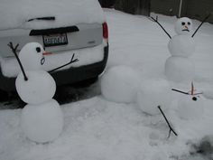 three snowmen are standing in the snow next to a car