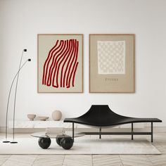 two abstract paintings hang on the wall above a black chair and table in a white room