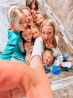 a group of young children standing next to each other in front of a bathroom mirror