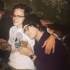 three young men sitting next to each other at a bar with drinks in their hands