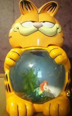 a yellow cat statue with a fish bowl in it's mouth and eyes closed