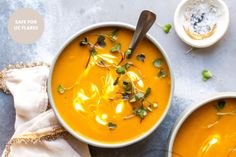 two bowls of carrot soup on a table