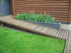 a wooden walkway leading to a house with flowers in the planters on each side